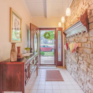 A welcoming foyer with a stone wall and open door leading to the outside.