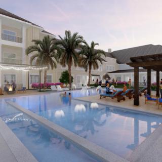 A serene hotel swimming pool area at dusk, surrounded by palm trees and comfortable seating.