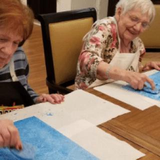 Two seniors enjoying a painting session together.