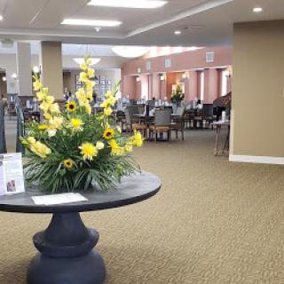 A welcoming lobby featuring a decorative floral arrangement on a round table, complemented by cozy seating and modern decor.