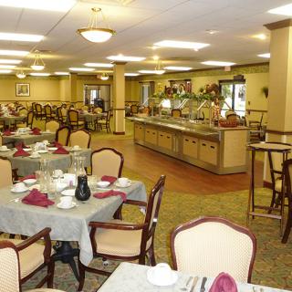 Spacious dining hall featuring neatly arranged tables and a self-service buffet area.
