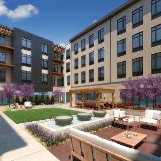 A modern apartment complex with a well-landscaped courtyard featuring outdoor seating and decorative elements.