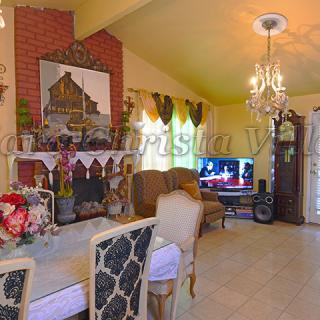 A cozy living room with elegant decor, featuring a chandelier, fireplace, and television.
