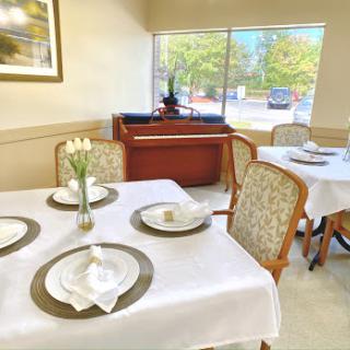 An elegantly arranged dining area featuring tables with fine tableware and a pleasant window view.