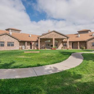 A well-maintained building with a grassy lawn and pathway under a cloudy sky.