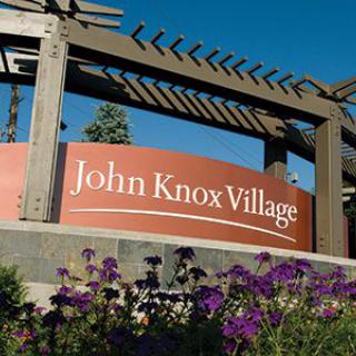 Entrance sign for John Knox Village surrounded by flowers.