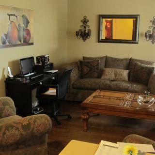 A cozy living room featuring a sofa, a coffee table, and a desk with a computer.