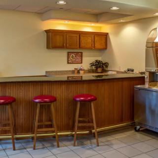 A cozy bar area with three red stools, a wooden counter, and overhead cabinets.