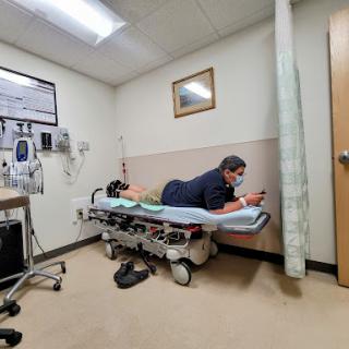 A patient in an emergency room, lying on a stretcher while using their phone.