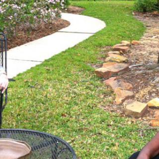 A scenic outdoor patio area with metal chairs overlooking a garden pathway.