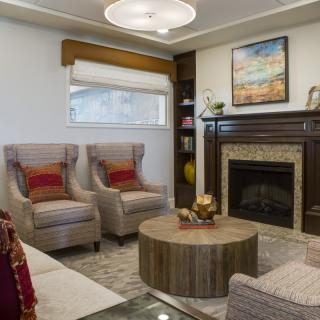 A cozy living room featuring a fireplace, armchairs, and a round coffee table adorned with decor items.
