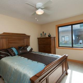 A cozy bedroom featuring a wooden bed and dresser, with natural light streaming through a large window.