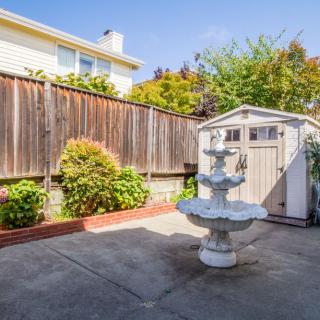 A peaceful backyard featuring a decorative fountain, a shed, and a well-maintained patio area.