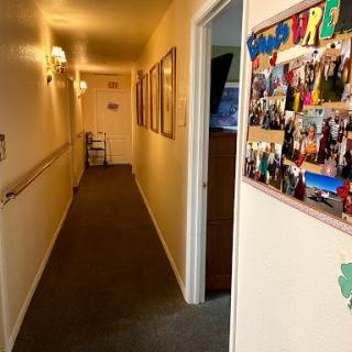 A well-lit hallway adorned with photographs and art, leading to various rooms.