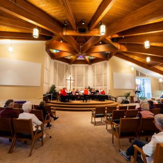 A concert taking place inside a church with an audience seated, showcasing the architectural design of the interior.