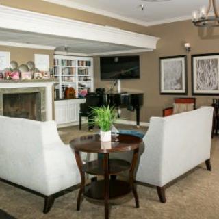 A cozy living room with a fireplace, two sofas, and a grand piano.