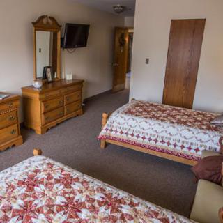 A cozy hotel room with two double beds and wooden furniture.