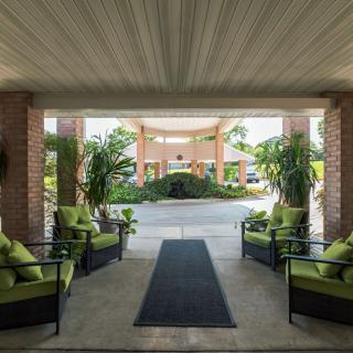 A covered entrance with comfortable seating and lush greenery welcomes visitors.