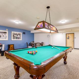 A well-lit game room featuring a pool table with cues and racked balls ready for play.