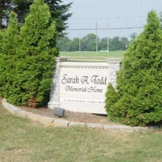 Stone memorial sign among trees in an outdoor setting.