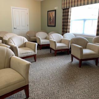 A well-organized waiting room with several beige armchairs and a carpeted floor.