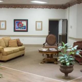 A cozy living room with sofas, a table, and decorative plants.