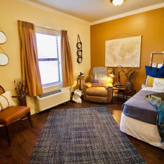 A cozy bedroom with warm colors, featuring an armchair, bed, and map wall art.