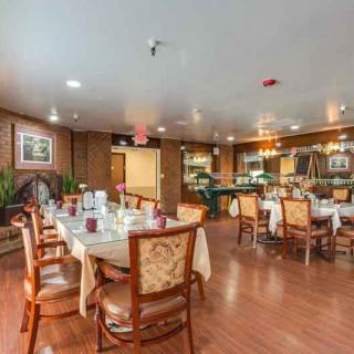 A warmly decorated dining room with elegantly set tables and comfortable chairs.