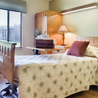 A cozy bedroom with a neatly made bed and a wooden desk by the window.