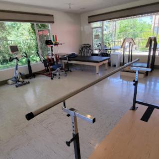 A bright and spacious gym area featuring various exercise equipment and a barre for workouts.