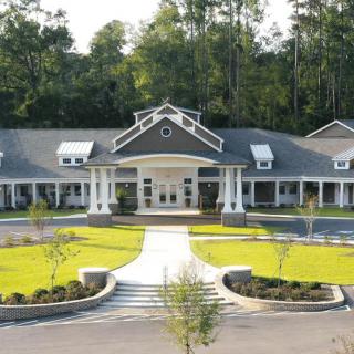 A symmetrical building with a landscaped entrance and surrounding greenery.