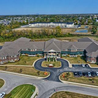 Aerial view of a large building with a circular driveway and parking lot in a suburban area.