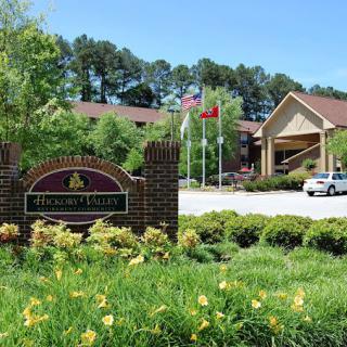 An outdoor view of a hotel with a sign, surrounded by lush landscaping and flags.