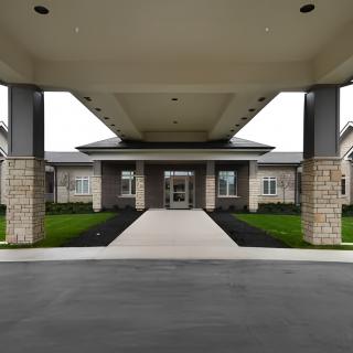A modern building entrance with a stone facade and a covered walkway.