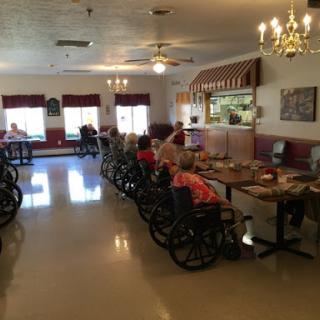 A dining area in a care facility where seniors are seated at tables.