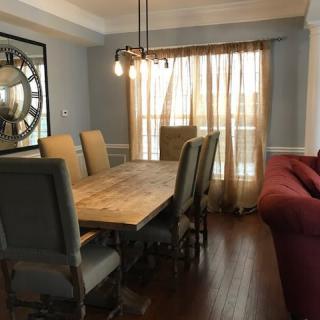 A cozy dining room with a rustic wooden table, upholstered chairs, and soft lighting.