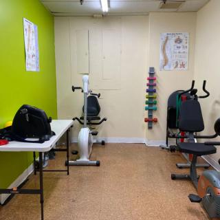 A small exercise room with fitness equipment including a stationary bike and various weights.