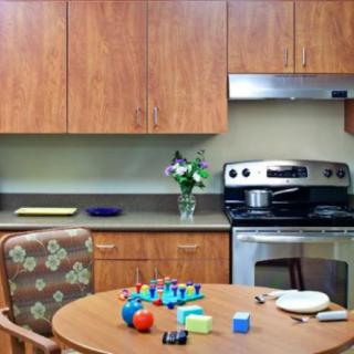 A cozy kitchen with wooden cabinets, a stove, and a table with toys and flowers.