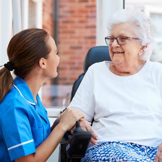 A nurse chatting with a senior woman in a comforting setting.