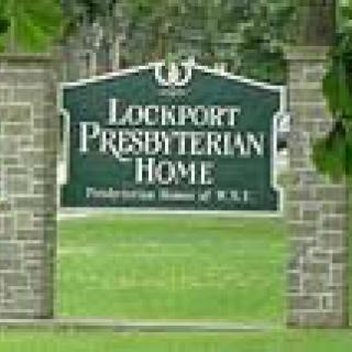A sign for Lockport Presbyterian Home displayed outdoors on a brick structure.