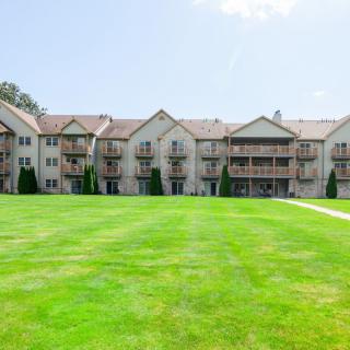 A large residential apartment building with a well-maintained green lawn in front.