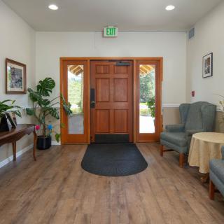 A welcoming entrance with wooden flooring, plants, and comfortable seating.