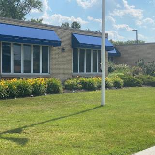 A well-maintained building with blue awnings and landscaped surroundings under a clear sky.