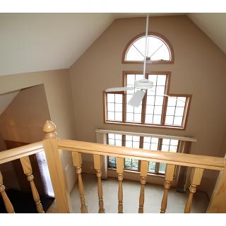 A view from a loft overlooking large windows and a high ceiling.