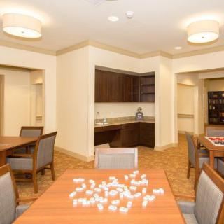 A well-lit dining area with tables and chairs, featuring a small kitchen section in the background.