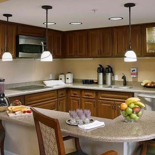 A modern kitchen with wooden cabinets, pendant lighting, and a cozy atmosphere.