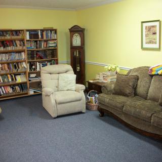 A cozy living room with a bookshelf, armchair, and sofa.