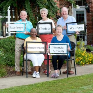A cheerful group holding signs representing various aspects of wellness and community support.