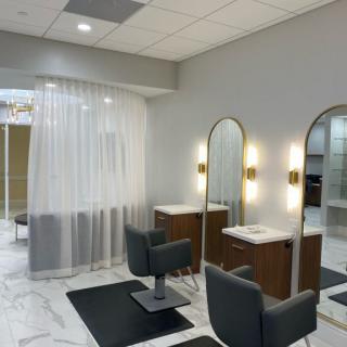 A modern salon interior with stylish chairs, mirrors, and soft lighting.