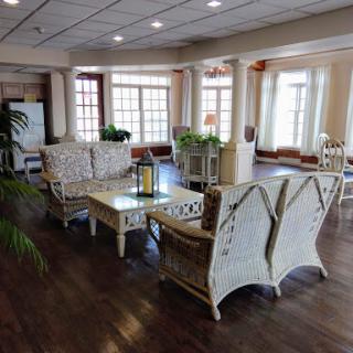 A cozy lounge area featuring comfortable seating, ample natural light, and decorative plants.